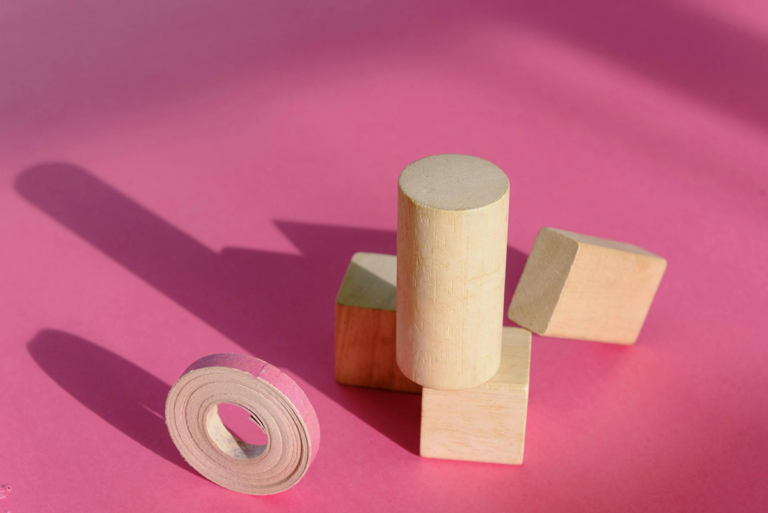 Wooden blocks balancing on a pink background